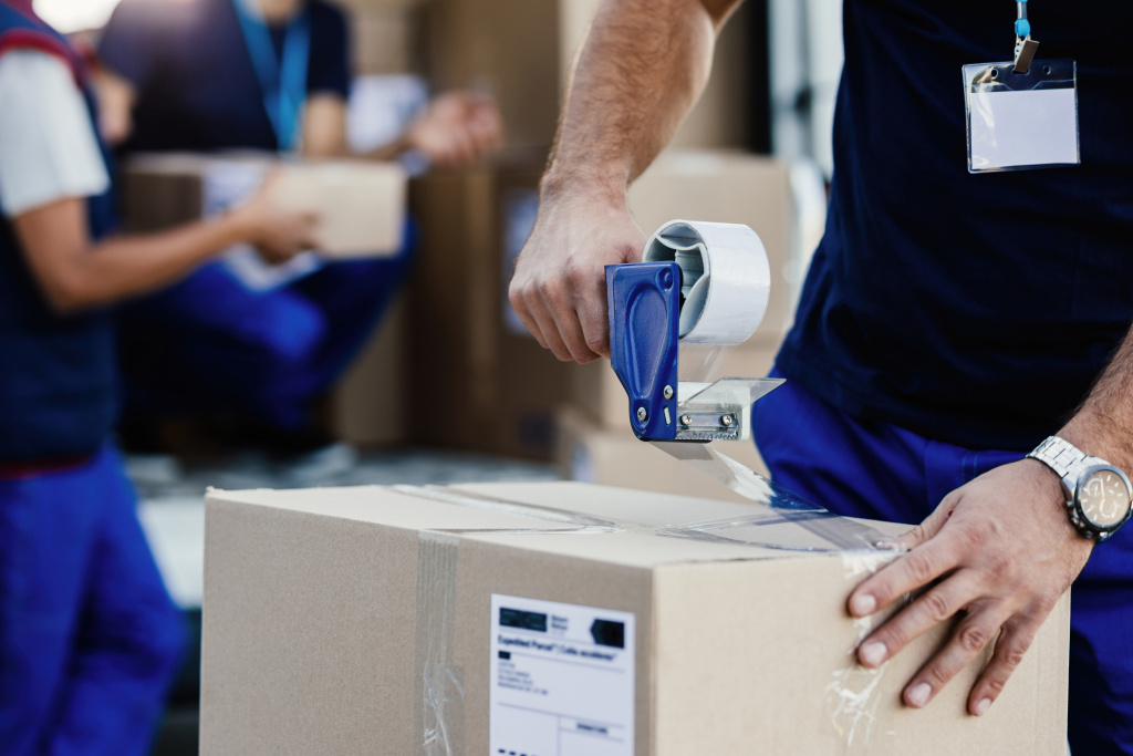 closeup-delivery-man-closing-carboard-box-with-tape-while-preparing-packages-shipment.jpg closeup-delivery-man-closing-carboard-box-with-tape-while-preparing-packages-shipment.jpg